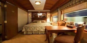Suite Junior du Maharajas Express avec lit double, boiseries luxueuses et vue panoramique en mouvement